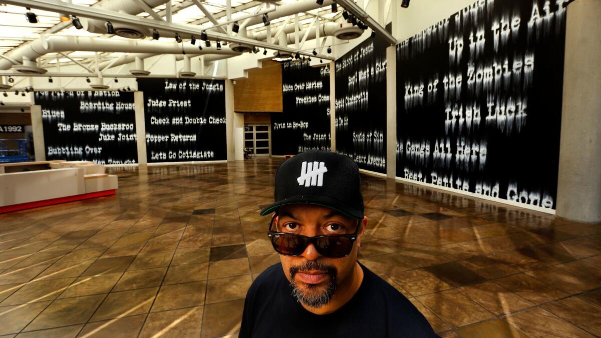 Artist Gary Simmons in front of his mural installation "Fade to Black" at the California African American Museum in Los Angeles.
