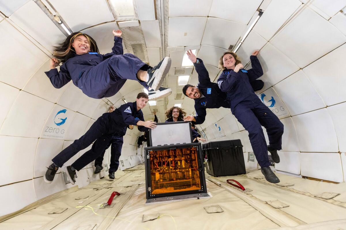 Six people float in the air in the padded fuselage of an airplane used to simulate a zero-gravity environment. 
