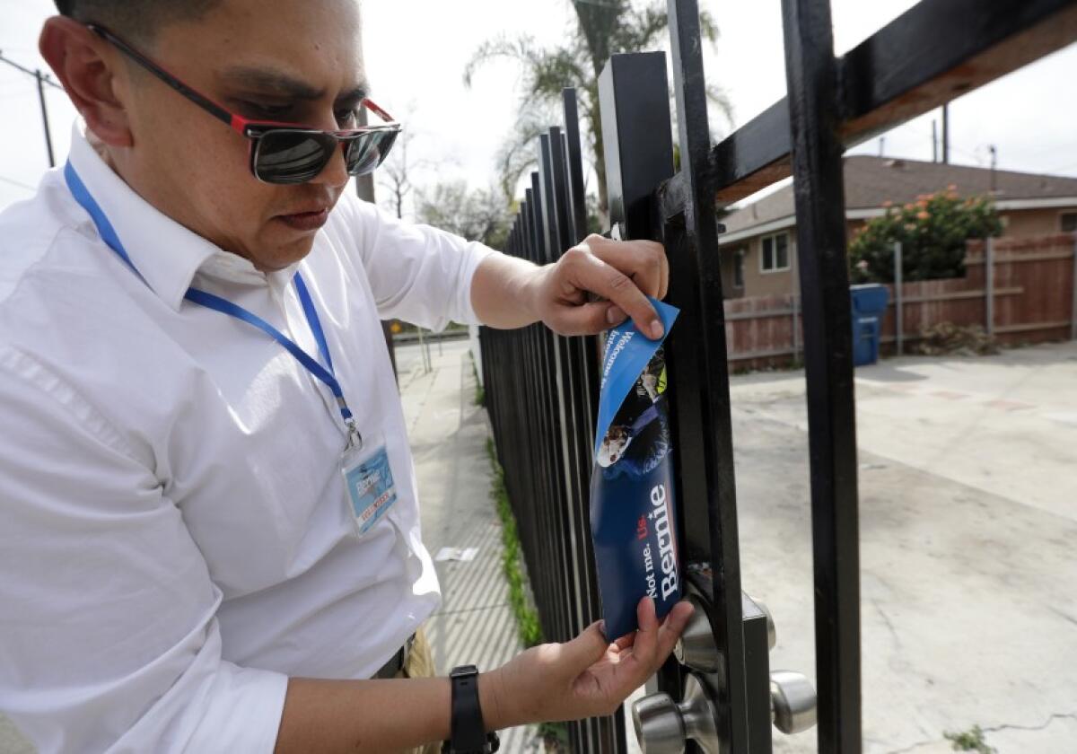 Ricardo Alonzo Ugalde places a flier on a gate while canvassing for Bernie Sanders in East Los Angeles in February