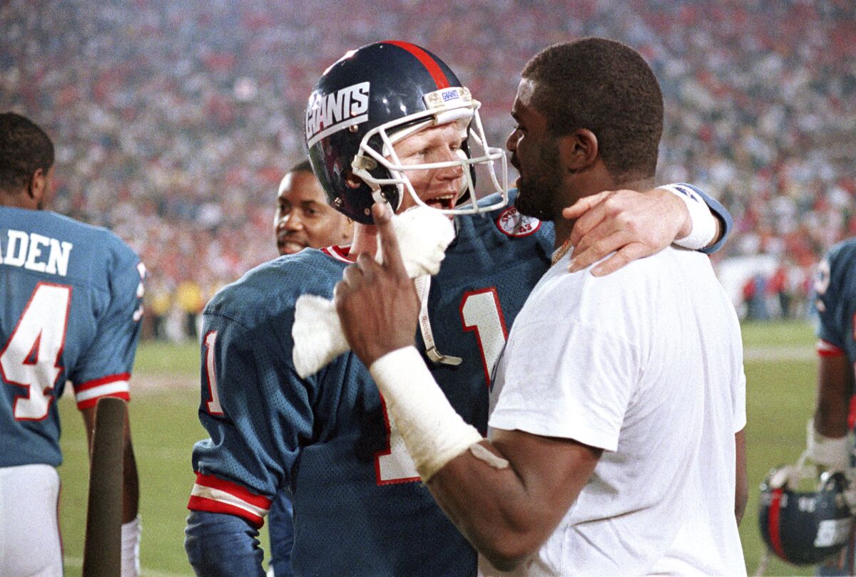 FILE - New York Giants quarterback Phil Simms (11) embraces linebacker Lawrence Taylor after they defeated the Denver Broncos to win NFL football's Super Bowl XXI game in Pasadena, Calif., Jan. 25, 1987. Simms grabbed the spotlight after usually operating in the shadow of Lawrence Taylor and the New York defense and passed the New York Giants to a 39-20 victory over the Denver Broncos in their first Super Bowl. (AP Photo/Peter Southwick, File)