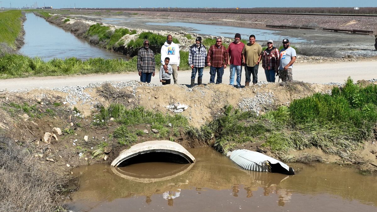 People stand next to a levee they fortified to prevent floodwaters from inundating their community in Allensworth, Calif.