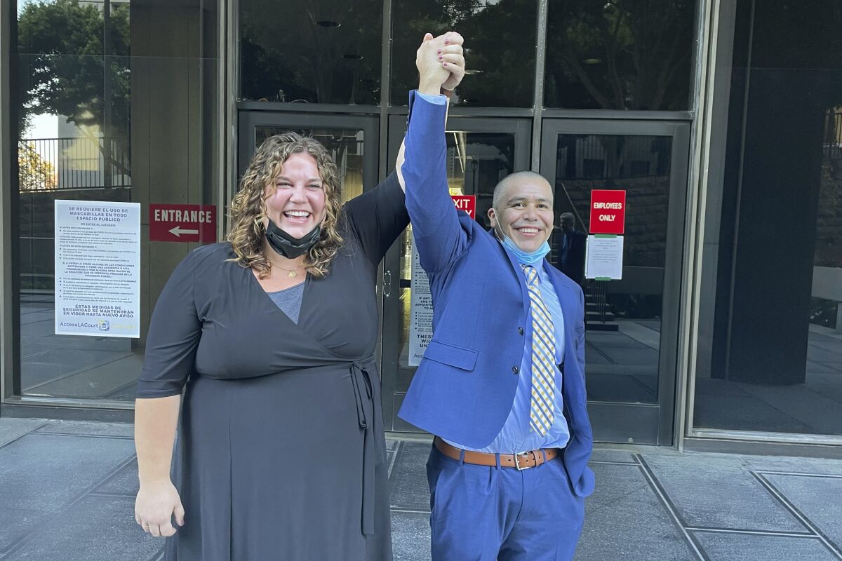 In this photo provided by the California Innocence Project, staff attorney Audrey McGinn raises her hand with Alexander Torres after he was released from a Criminal Justice Center in Los Angeles on Oct. 19, 2021. A California man who spent 21 years in prison for a gang murder he said he didn't commit has been declared factually innocent by a judge, authorities announced Wednesday, June 1, 2022. Torres appeared at a news conference with Los Angeles County District Attorney George Gascón and members of the California Innocence Project, which fought for his exoneration. (Jasmin Harris/California Innocence Project via AP)