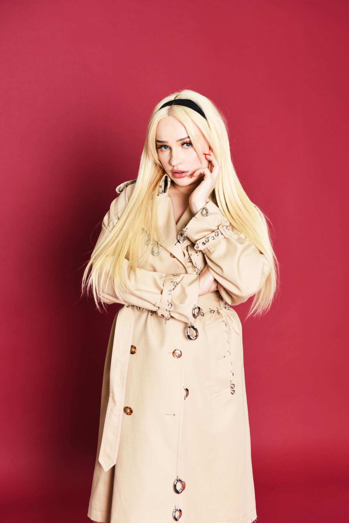 Kim Petras stands against a red background.