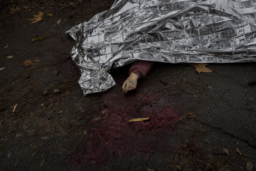 The body of a woman killed during a Russian attack is covered with an emergency blanket before being transported to the morgue in Kherson, southern Ukraine, Friday, Nov. 25, 2022. A barrage of missiles struck the recently liberated city of Kherson for the second day Friday in a marked escalation of attacks since Russia withdrew from the city two weeks ago following an eight-month occupation. (AP Photo/Bernat Armangue)
