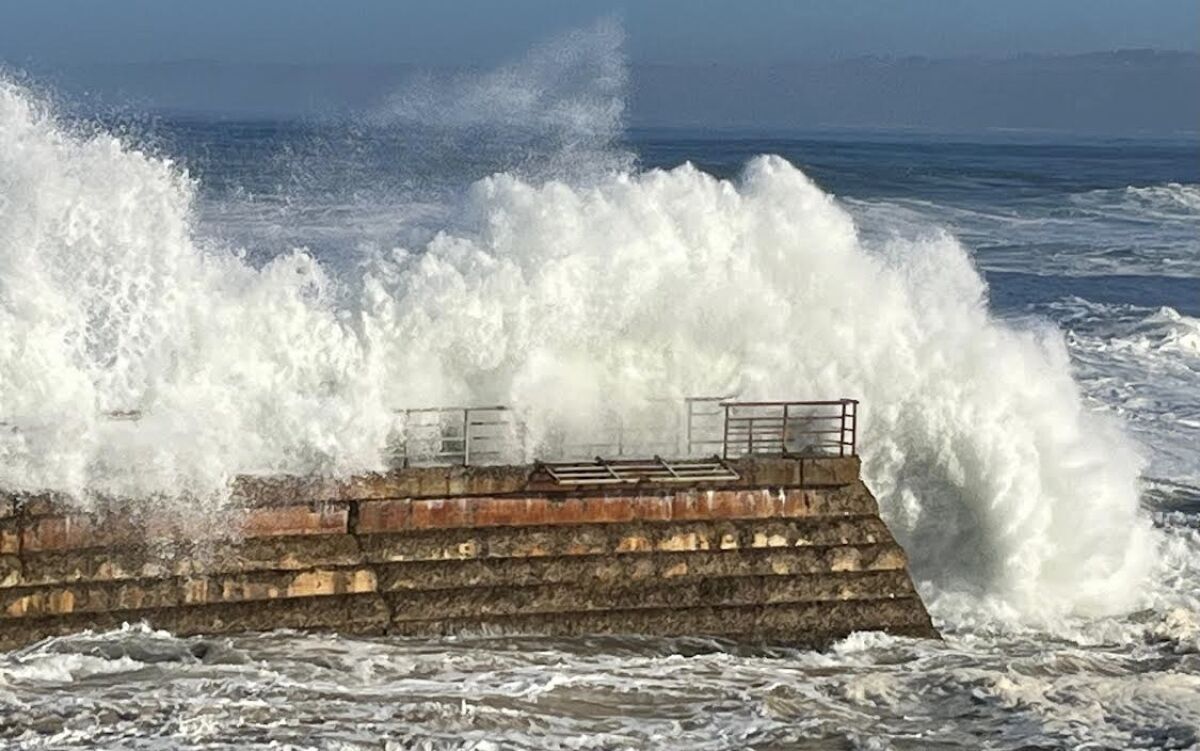 Big waves smack the seawall at the Children's Pool during stormy weather in January, causing damage to a safety railing.