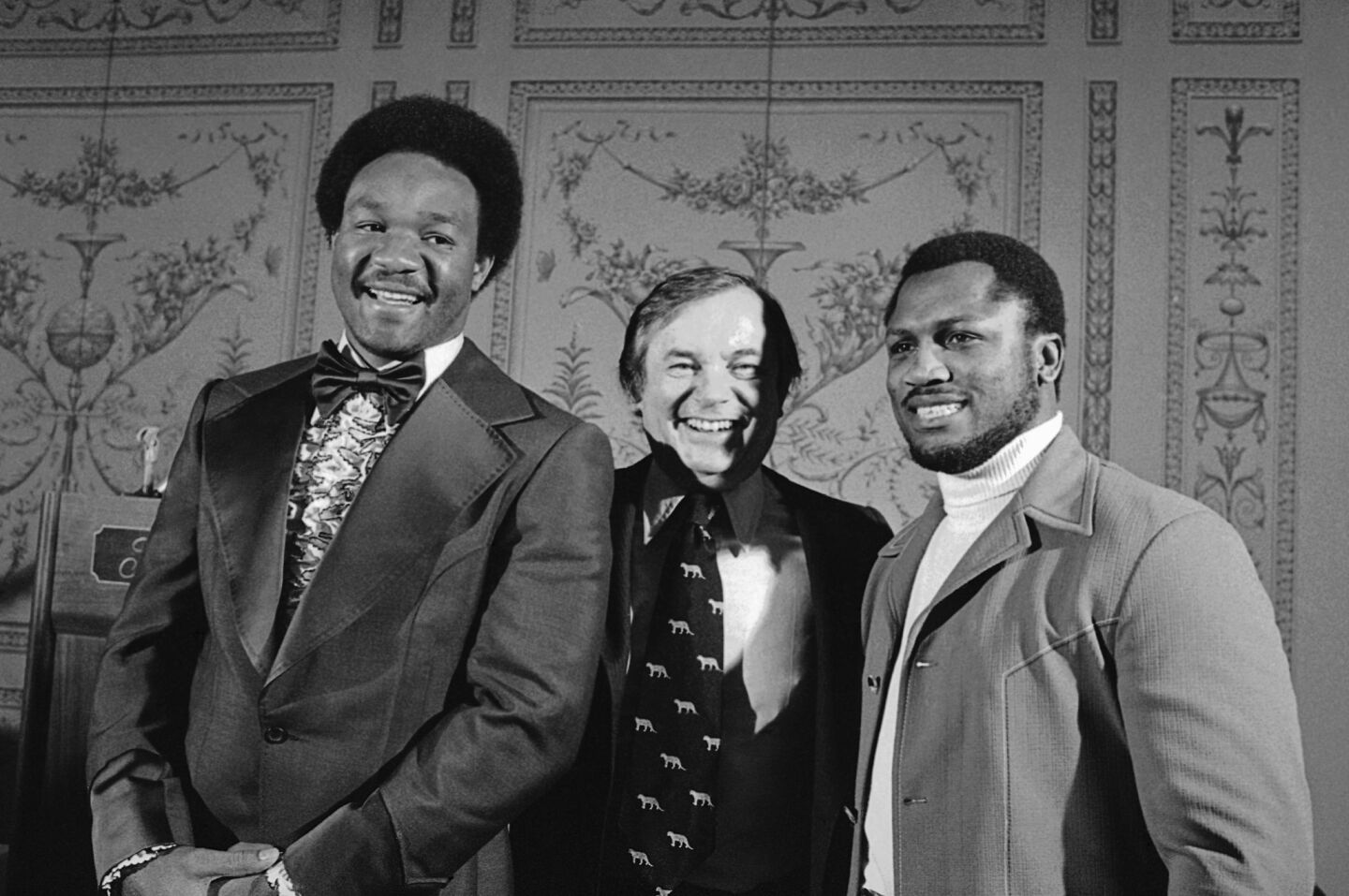 Former heavyweight champions George Foreman, left, and Joe Frazier, right, stand with promoter Jerry Perenchio in New York in April 1976 when it was announced they would meet that year in June for a boxing match.