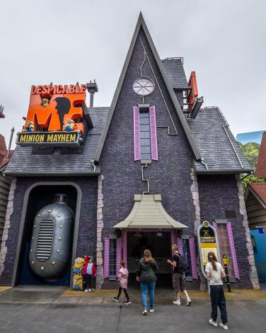A tall, pointy gray house with purple trim is the entrance to Despicable Me Minion Mayhem ride at Universal Studios.