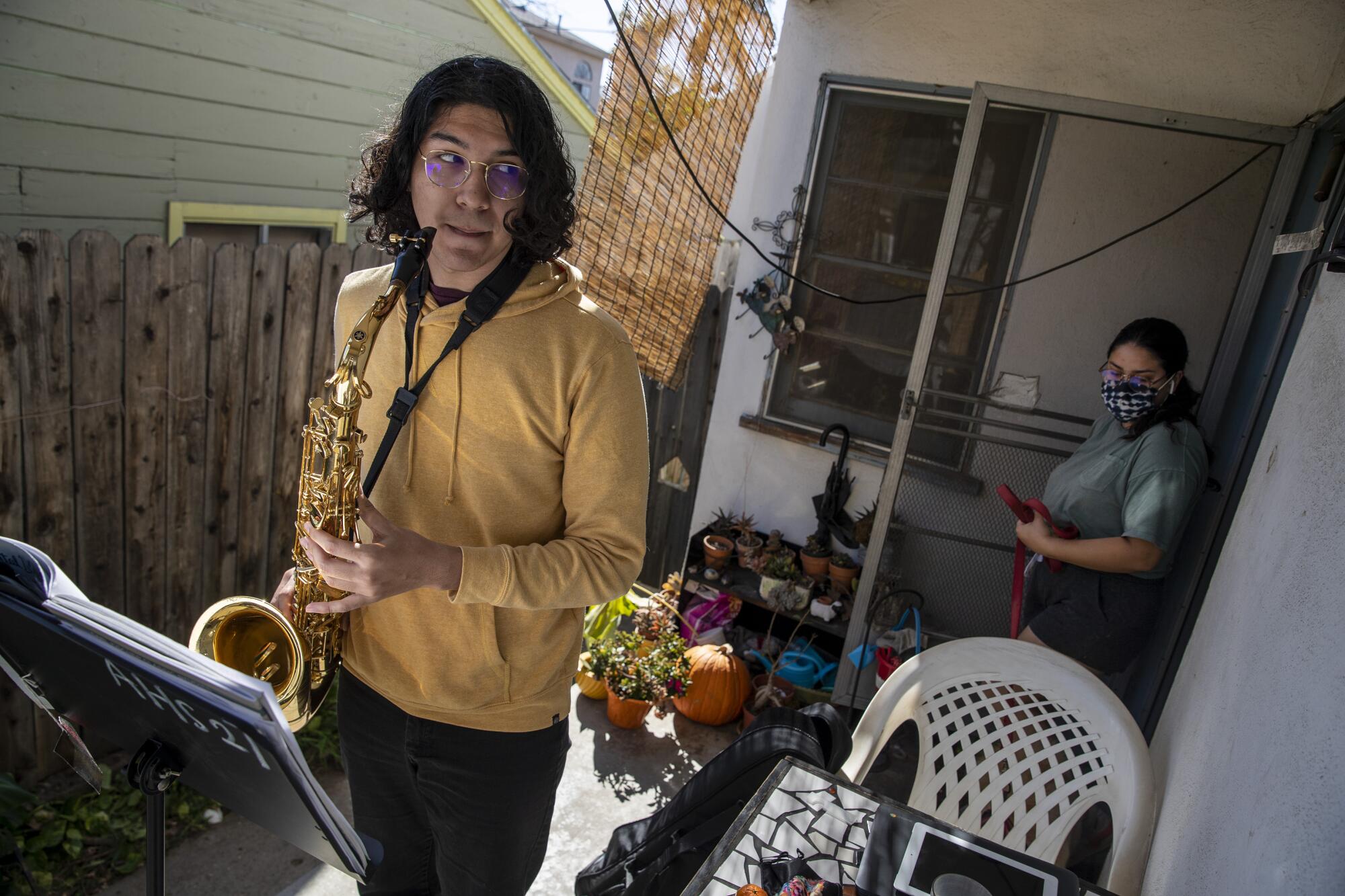 A student holds a saxophone on a house's front porch