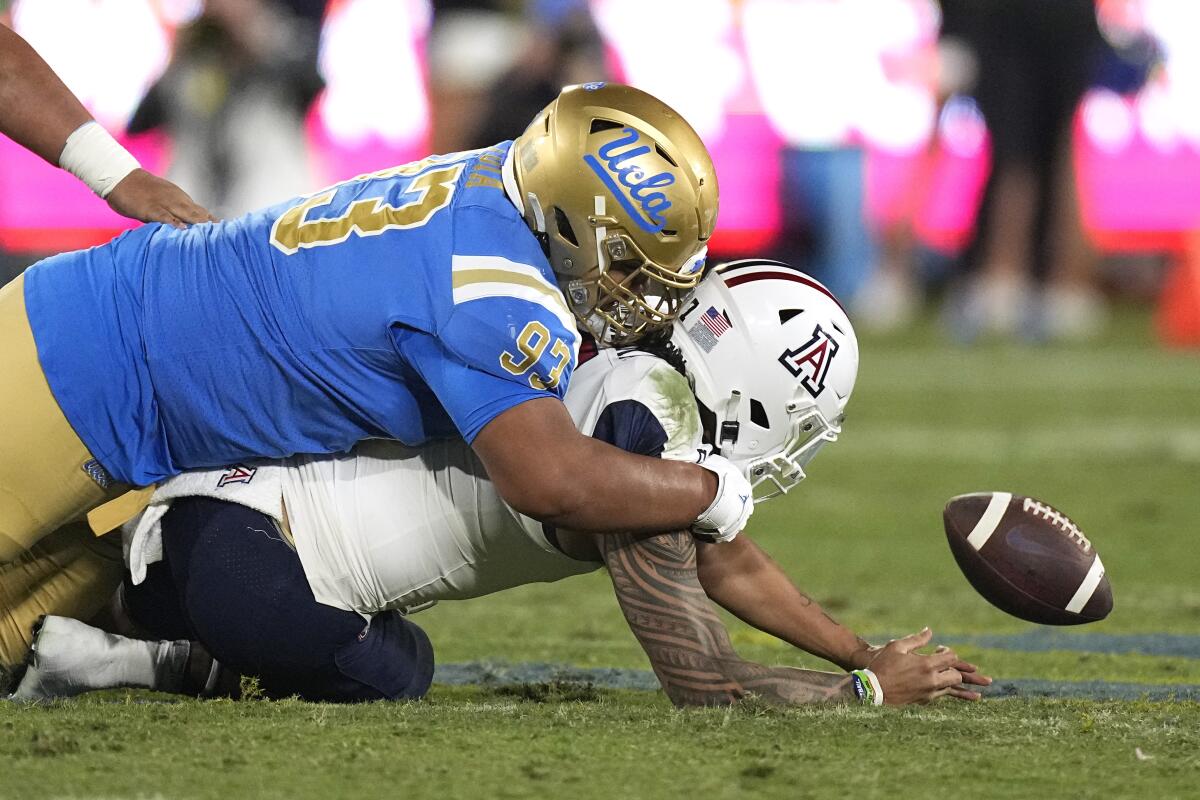 Arizona quarterback Jayden de Laura fumbles the ball while being tackled by UCLA defensive lineman Jay Toia 