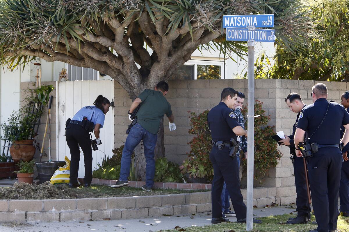 Investigators search the yard of a home at Matsonia Lane and Constitution Drive in Huntington Beach, March 17, 2022.