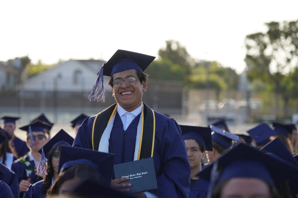 A new graduate displays his diploma with pride during Thursday's commencement held at Davidson Field.