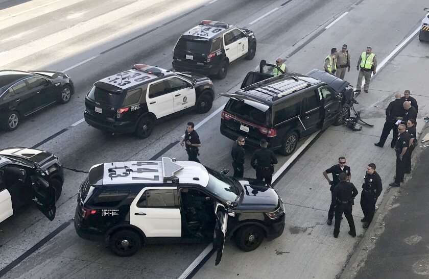 Police cars surround a crashed SUV on the freeway