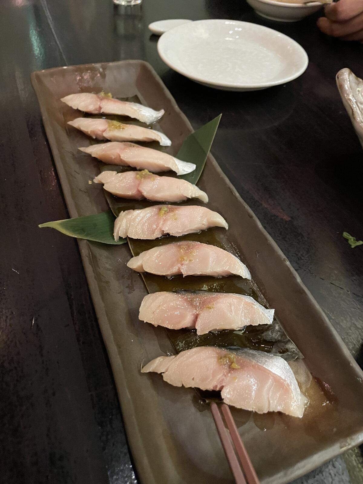 Slices of cured fish on a rectangular serving dish.
