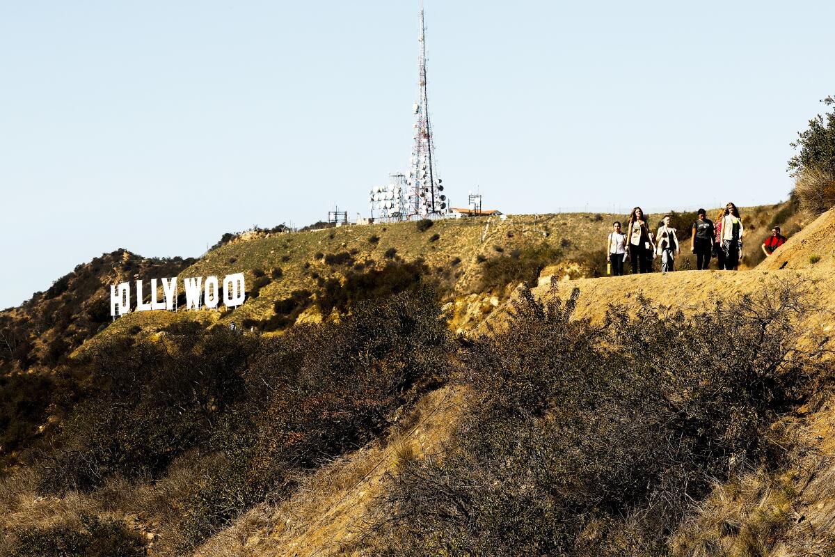 People hiking to the right of the Hollywood sign.