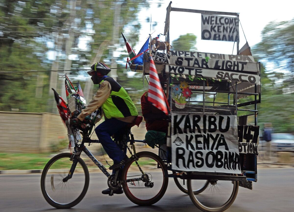 An man on a bicycle pulls a trailer with messages welcoming President Obama to Kenya in Nairobi on Thursday.