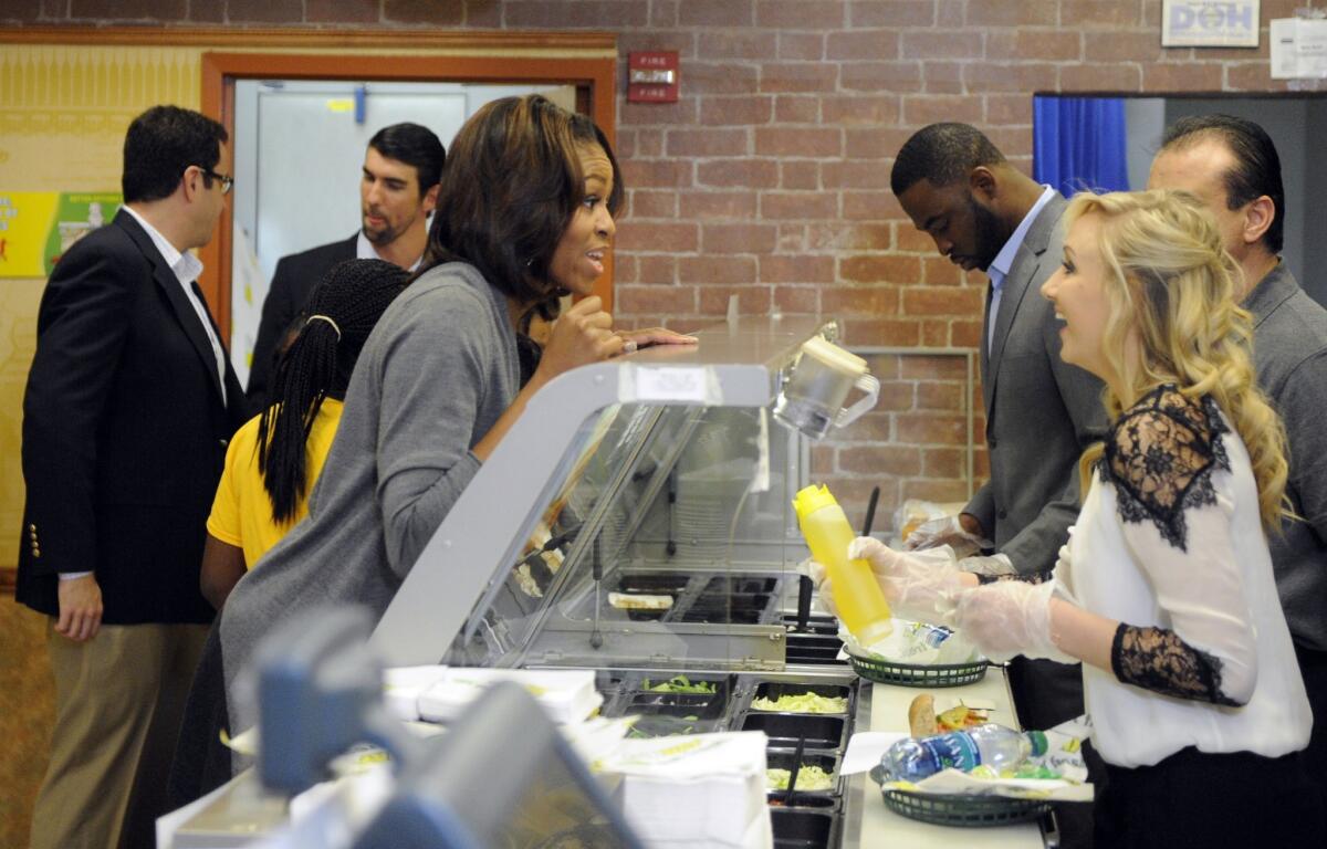 First Lady Michelle Obama, left, orders a sandwich from a Subway restaurant.