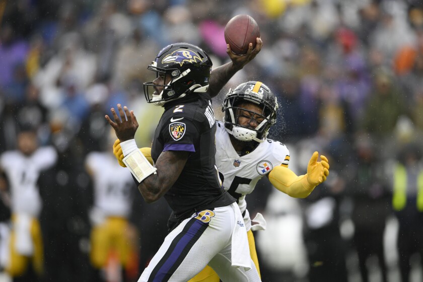 Water sprays off the helmet of Pittsburgh Steelers cornerback Arthur Maulet, right, as he prepares to make a hit on Baltimore Ravens quarterback Tyler Huntley during the first half of an NFL football game, Sunday, Jan. 9, 2022, in Baltimore. (AP Photo/Nick Wass)