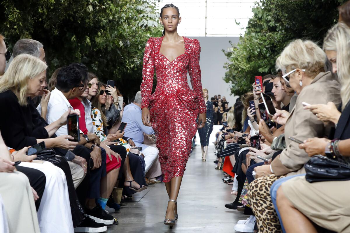 A runway model in a star-spangled red dress by Michael Kors
