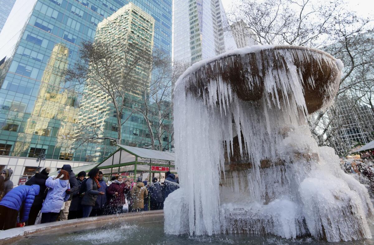 People pose for photographs in front of a frozen water fountain in New York's Bryant Park.