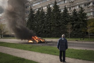 A man watches a burning car after Russian shelling in Kharkiv, Ukraine, on Thursday.