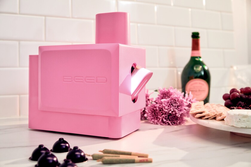 A pink joint-rolling machine on a kitchen counter next to some pot-filled aluminum pods