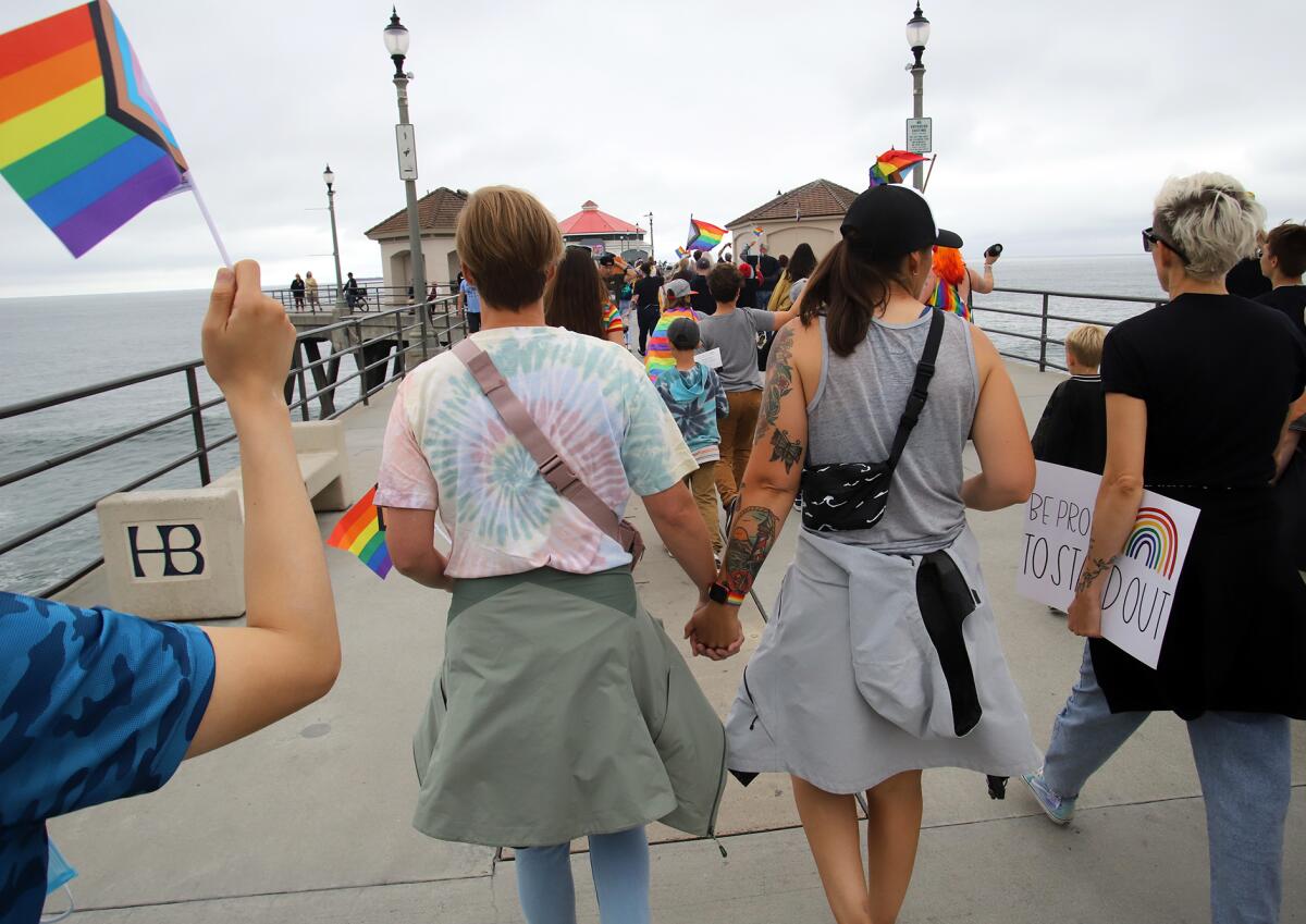 Local activists walk to the end of the Huntington Beach Pier during an LGBTQ+ demonstration last month.