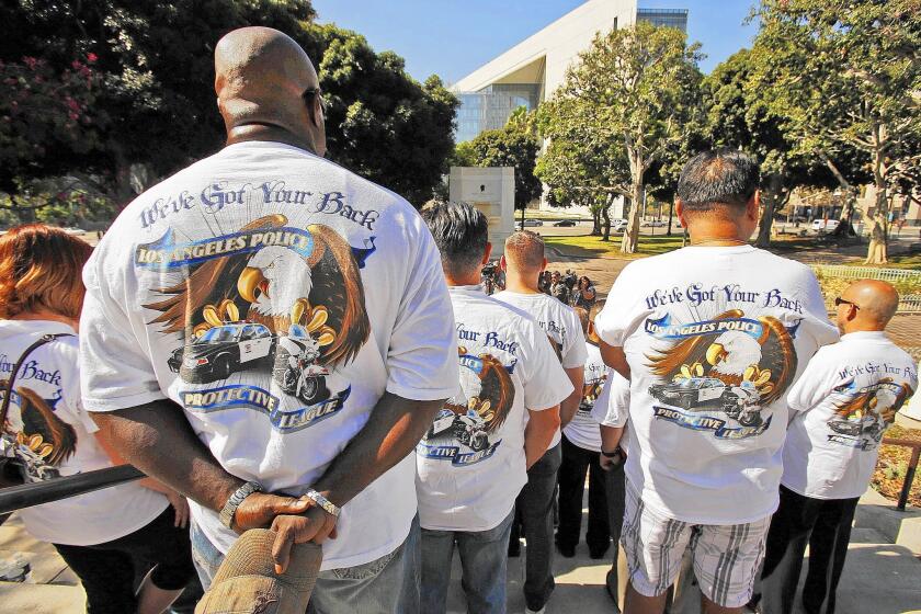Officer Dwayne Wilson, left, joins LAPD members wearing shirts in support of the Los Angeles Police Protective League during a press conference at City Hall.