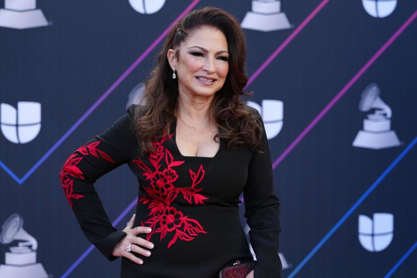 A woman with long red hair posing in a black dress with red accents