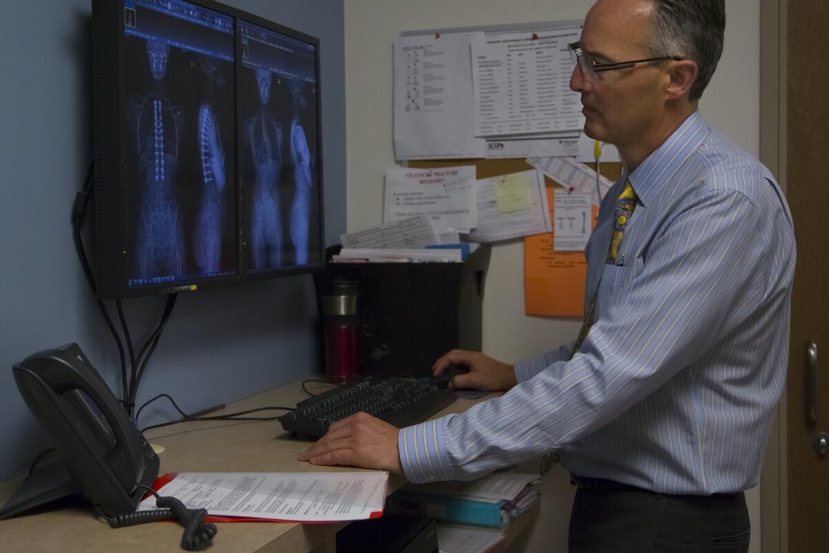 Dr. Peter Newton looks over digital x-rays on a large screen of his patient at Rady Children's Hospital. — Nelvin C. Cepeda / San Diego Union-Triubune / Twitter @NelCepeda