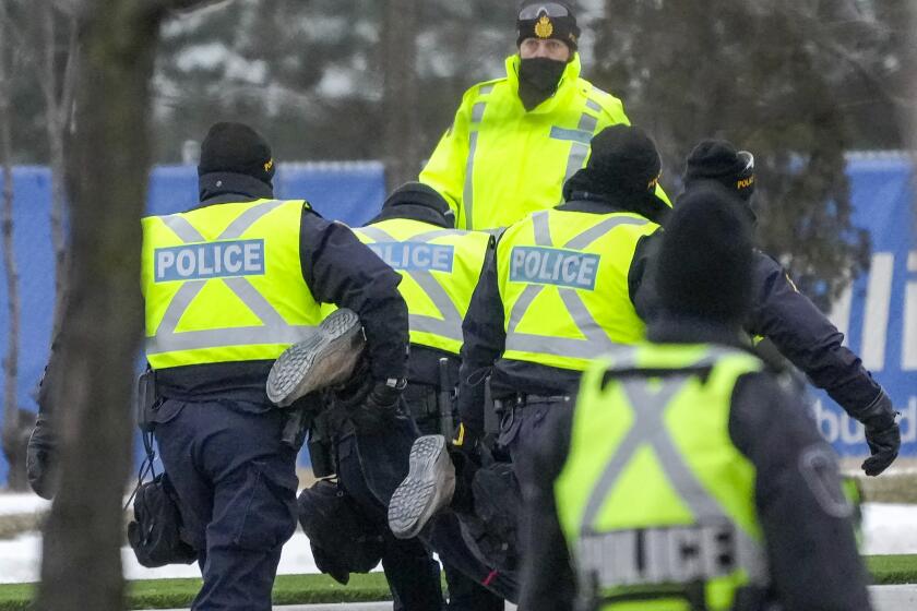 Police arrest a person Sunday in Ontario, Canada, where officers cleared the path to the Ambassador Bridge.