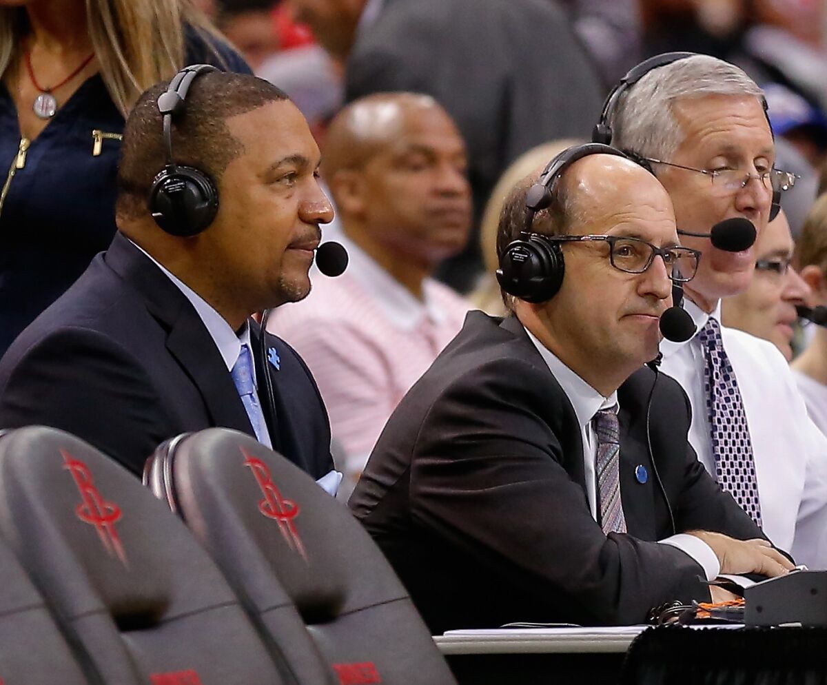 Marc Jackson and Jeff Van Gundy wear headsets as they watch a game.