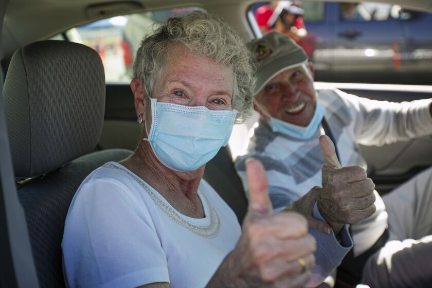 Fontana, CA - February 02: Hulene Dykstra, left, with her husband Heinz Beer, in an upbeat mood after getting her first dose of Moderna mRNA-1273 at a super COVID-19 vaccination site established by San Bernardino Public Health Department, for a day at Auto Club Speedway on Tuesday, Feb. 2, 2021 in Fontana, CA.(Irfan Khan / Los Angeles Times)