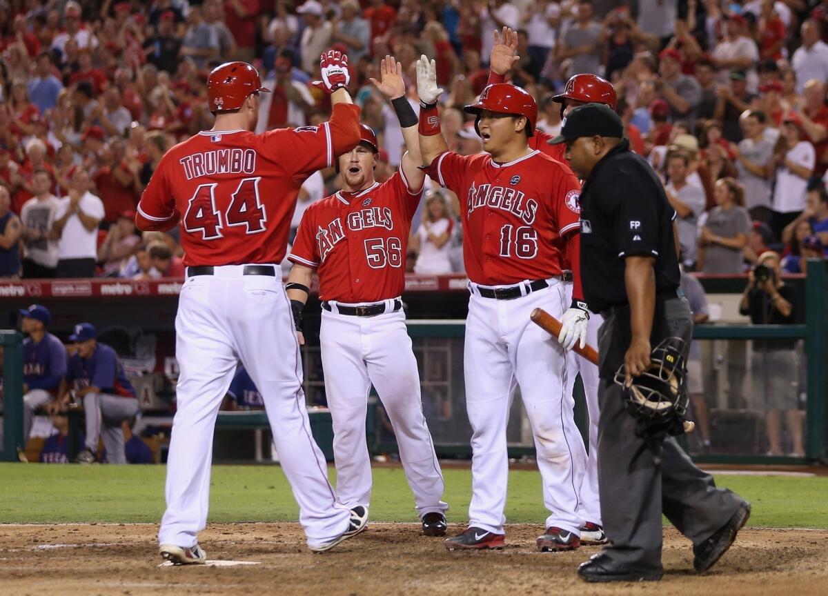Mark Trumbo, left, is congratulated by teammates Kole Calhoun, center, and Hank Conger after hitting a three-run home run during the fourth inning of the Angels' 6-5 win over the Texas Rangers on Friday.