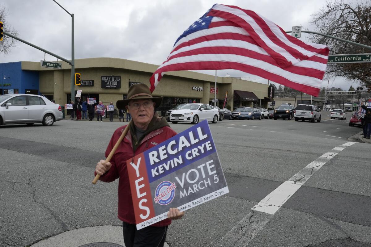 A man carrying an American flag holds a sign calling for the recall of Shasta County Supervisor Kevin Crye.