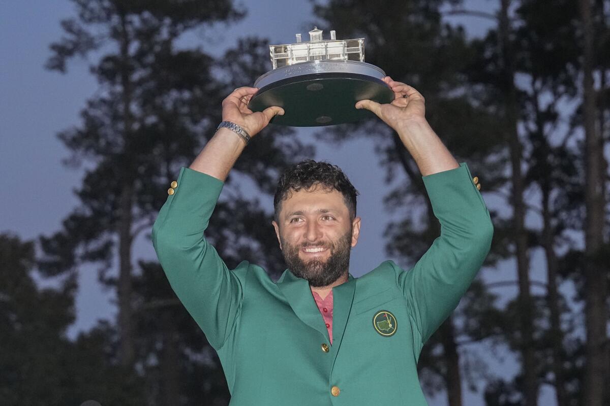 Jon Rahm holds the Masters trophy over his head after winning the golf tournament at Augusta National Golf Club.