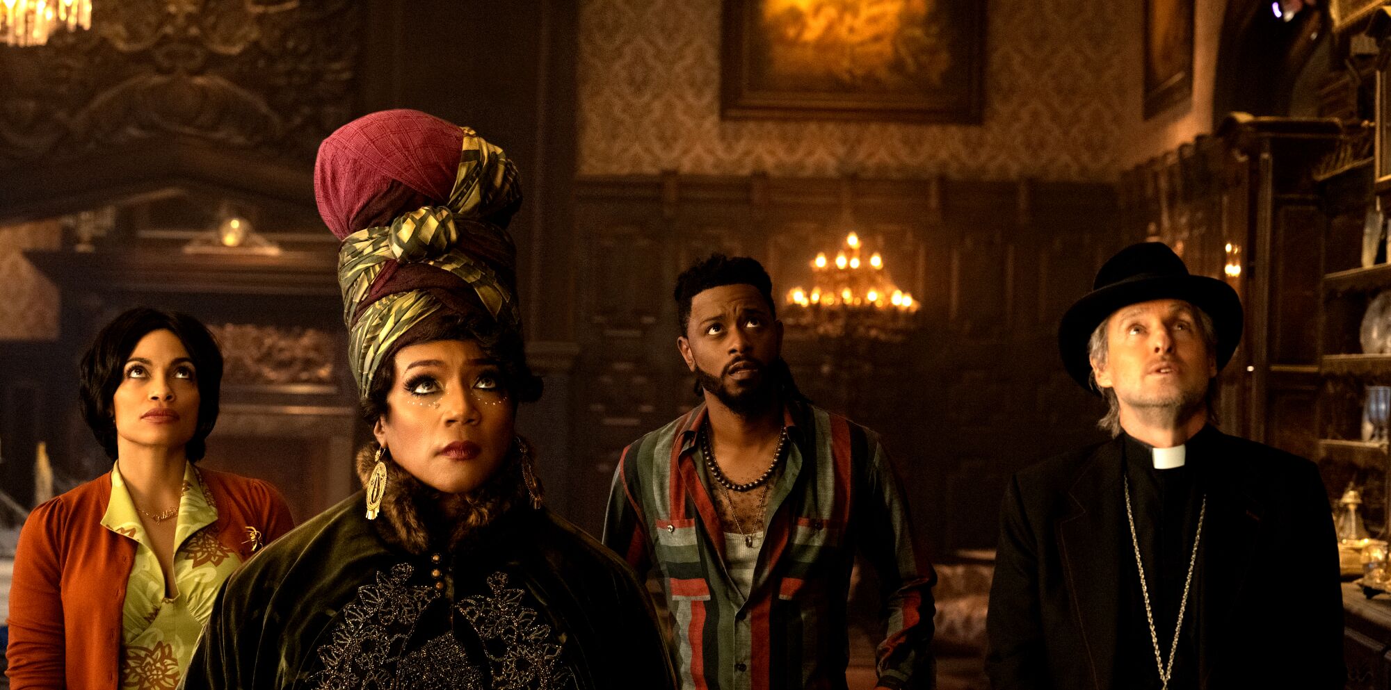 Four people look up at the ceiling in an old mansion.