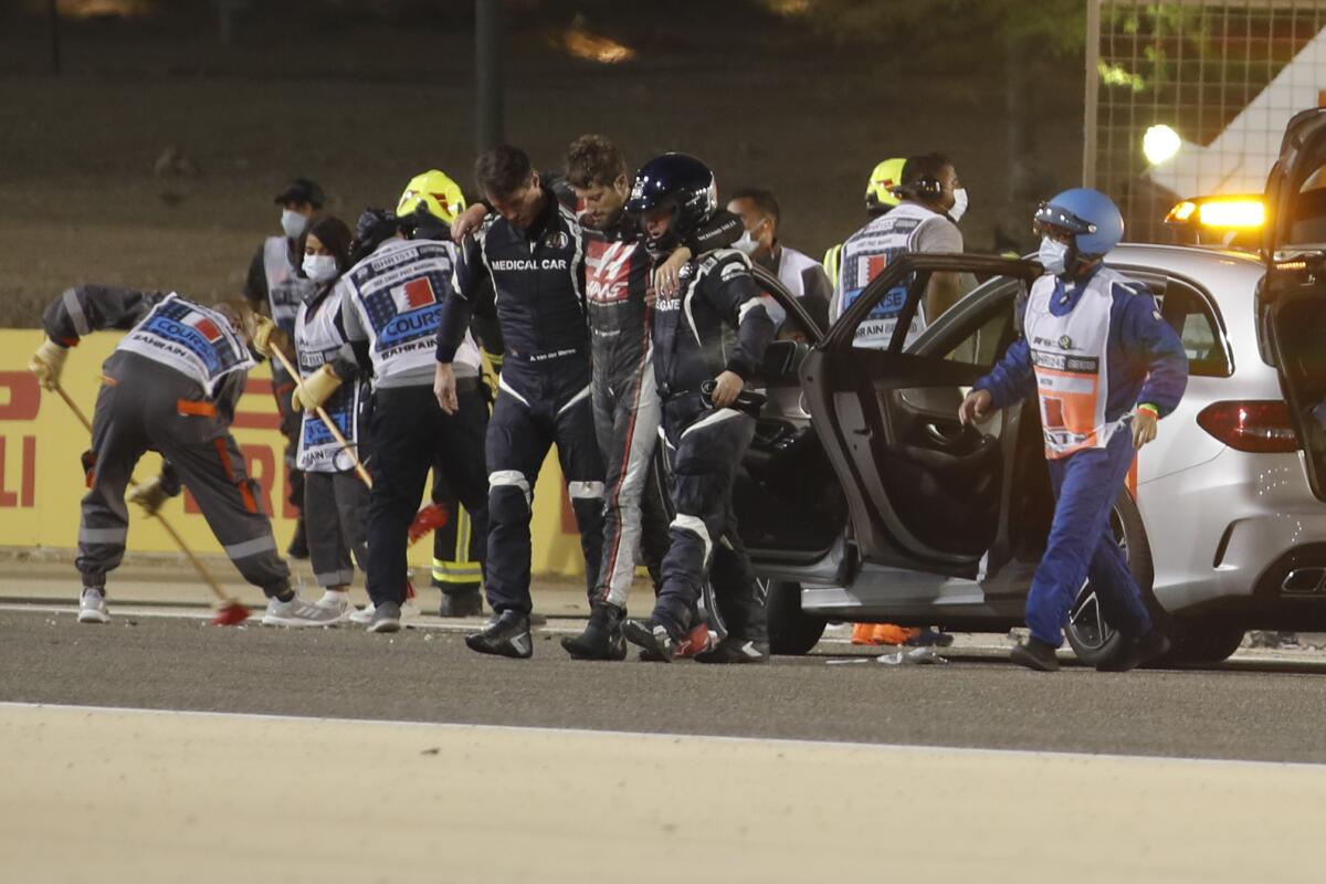 Haas driver Romain Grosjean is helped by medical staff after his crash at the Bahrain Grand Prix.