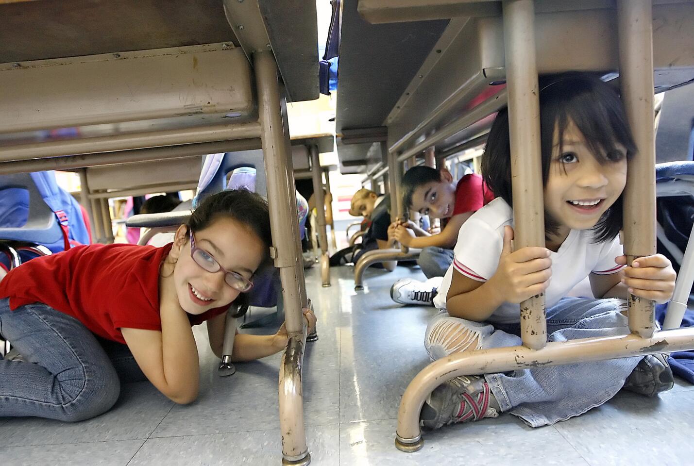 Romina Shabany, 6, and Cierra Quinto, 6, take cover under their desks during the Great California Shakeout earthquake drill on Thursday, October 20, 2011.