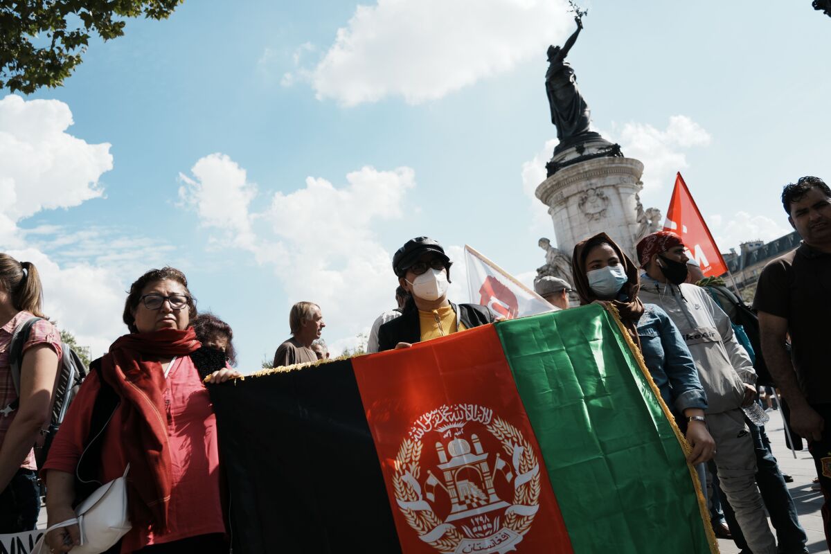 Women hold a flag of Afghanistan during a gathering in a show of solidarity with women from Afghanistan, Sunday, Sept. 5, 2021 in Paris. The Taliban have promised an inclusive government and a more moderate form of Islamic rule than when they last ruled the country from 1996 to 2001. But many Afghans, especially women, are deeply skeptical and fear a rollback of rights gained over the last two decades. (AP Photo/Thibault Camus)