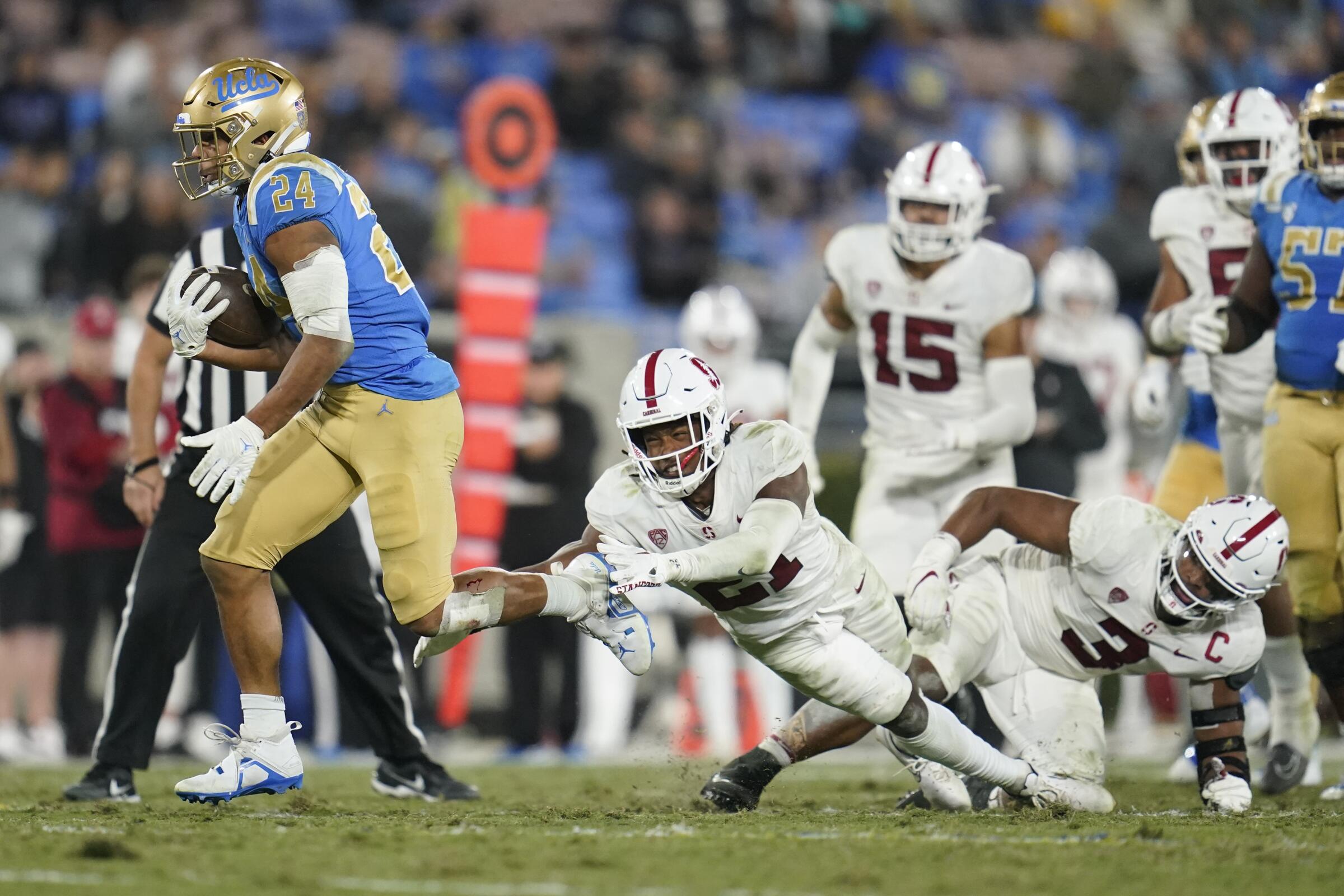 UCLA running back Zach Charbonnet (24) escapes tackle attempts by Stanford's Kendall Williamson and Levani Damuni. 