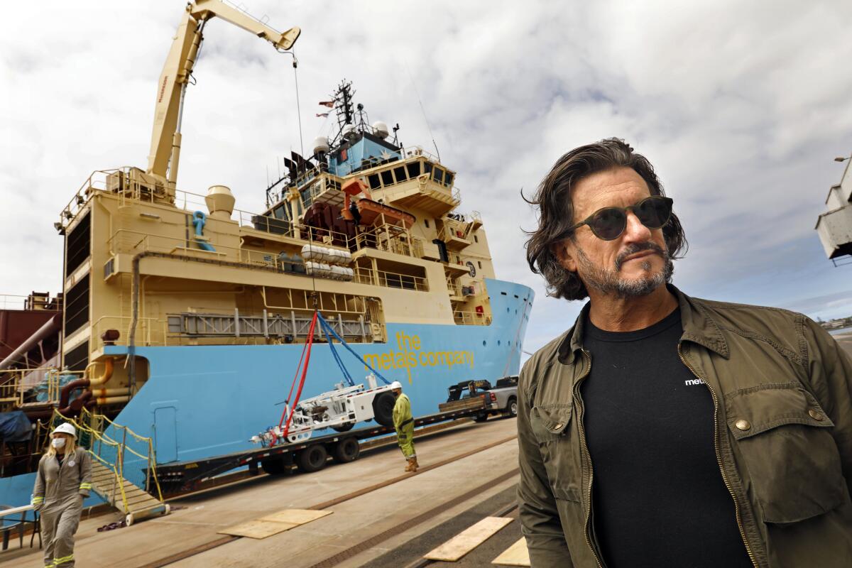 A man stands beside a research vessel at a pier.