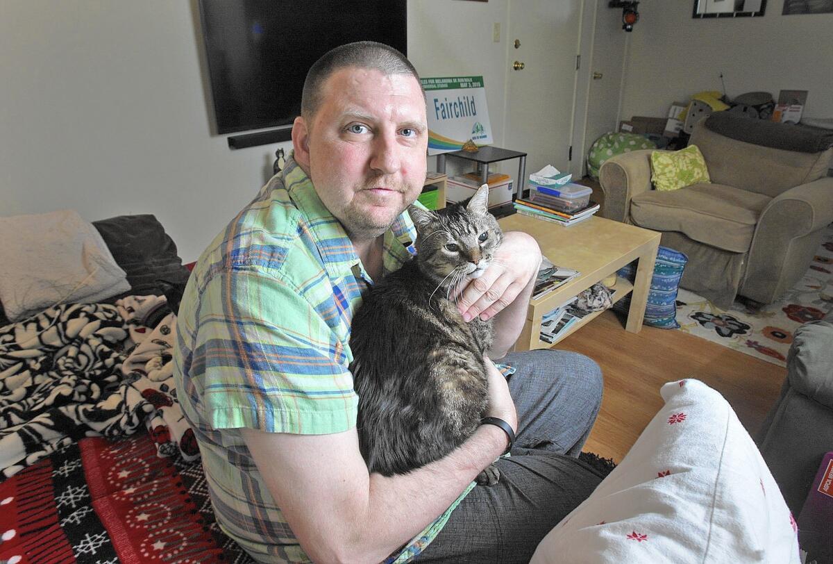 Matt Fairchild, 46, rests at his home in Burbank with his cat Jacques on Thursday, March 31, 2016. Fairchild has been living with stage IV melanoma for about two years and experiences some kind of pain throughout his body on a daily basis.