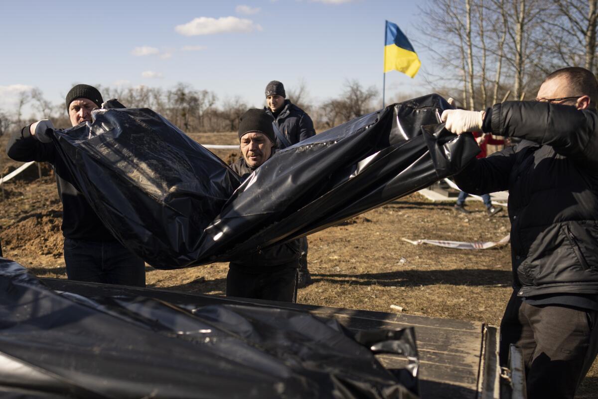 Men carry bags containing three freshly exhumed bodies in a cemetery on the outskirts of Borodyanka, Ukraine.