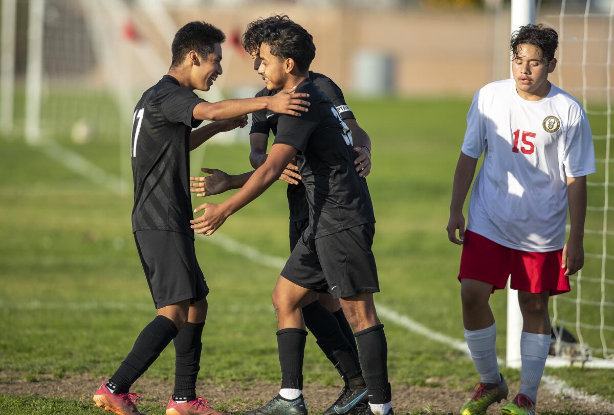 Los Amigos' Anthony Gutierrez, left, and Omar Arciga, behind, congratulate Humberto Rincon after he scores a goal.