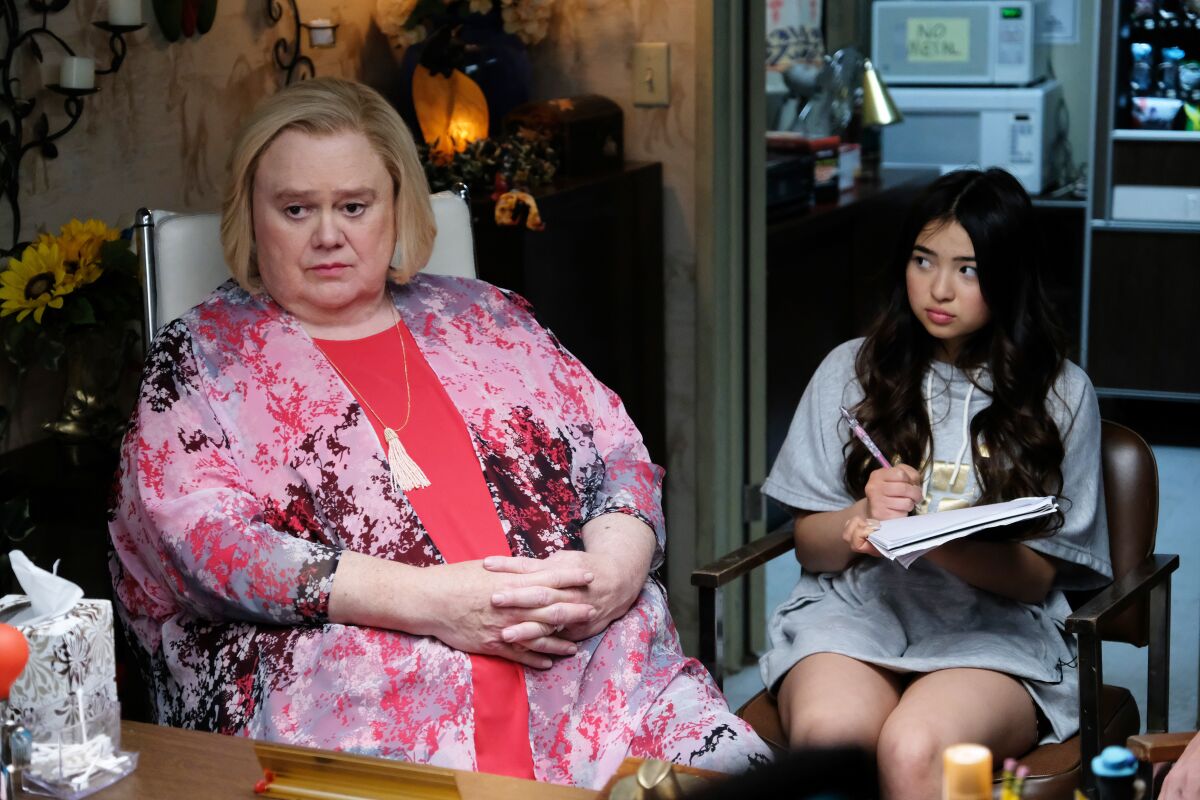 A man in drag and a younger woman sitting