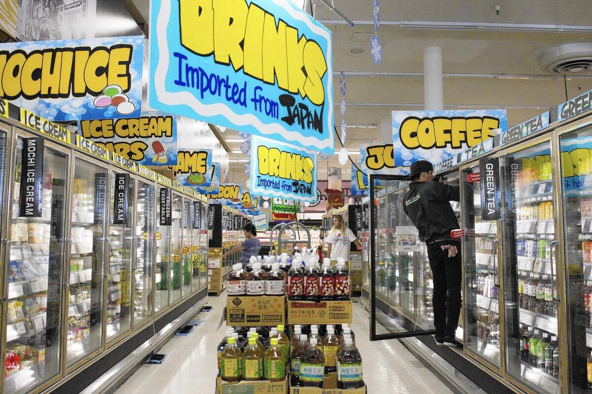 An employee restocks an upper shelf of the frozen dessert aisle at Tokyo Central in Costa Mesa. The store, which had been Marukai, is reporting more Americans coming in to shop than before.