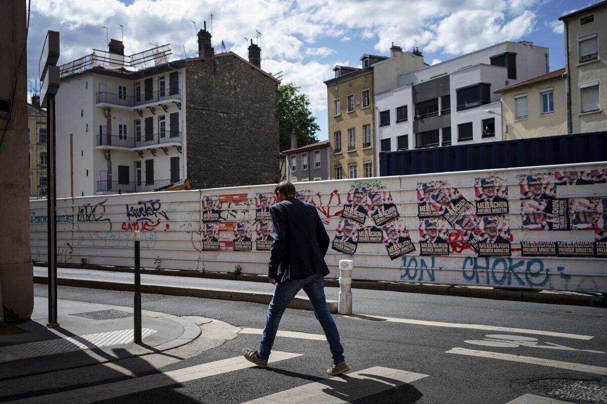 A man passes by electoral posters reading "Melenchon Prime Minister" in Lyon, central France, Tuesday, June 7, 2022. The legislative elections will take place on June 12 and 19, 2022. (AP Photo/Laurent Cipriani)