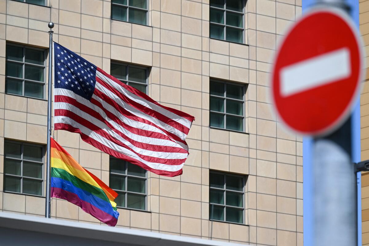 A U.S. flag flies above a rainbow flag on a flagpole