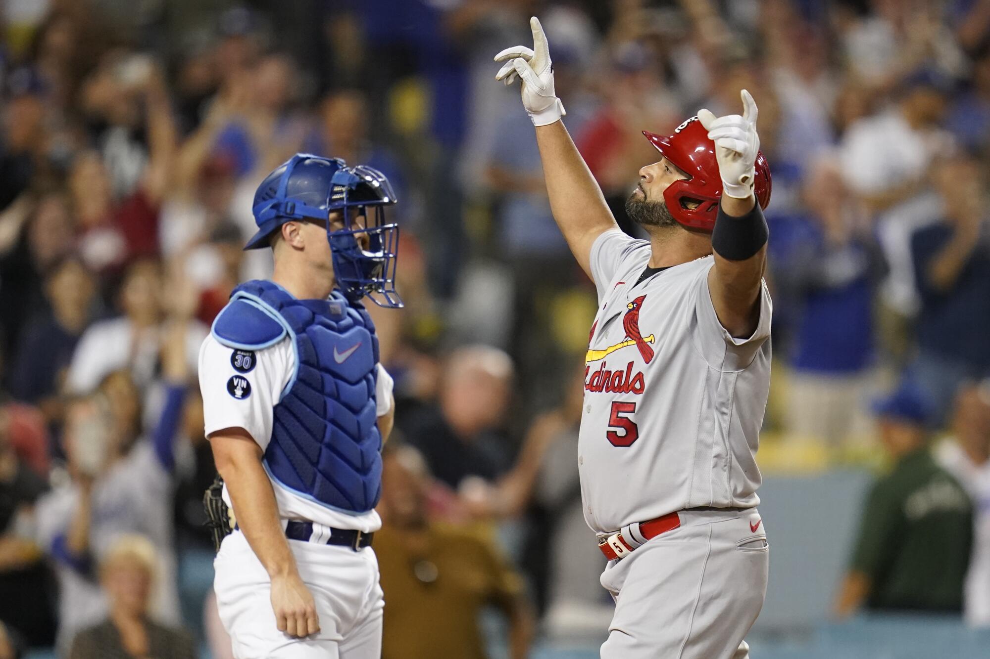 Albert Pujols raises his arms to the sky as he crosses home plate after hitting his 699th career home run against the Dodgers