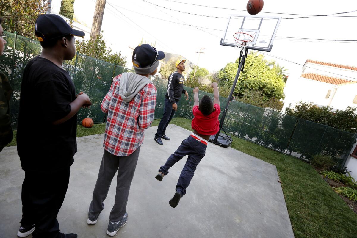 Children play on the newly constructed basketball court, along with Lakers forward Metta World Peace, who is near the basket, at the Door of Hope transitional apartment complex for women and children who have been left homeless as a result of domestic violence.
